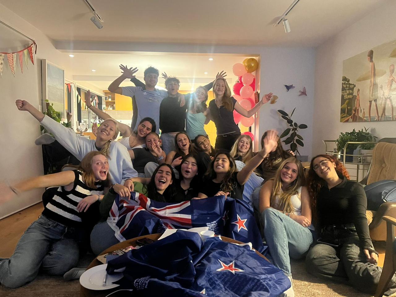 Grupo de estudiantes internacionales celebrando con la bandera de Nueva Zelanda